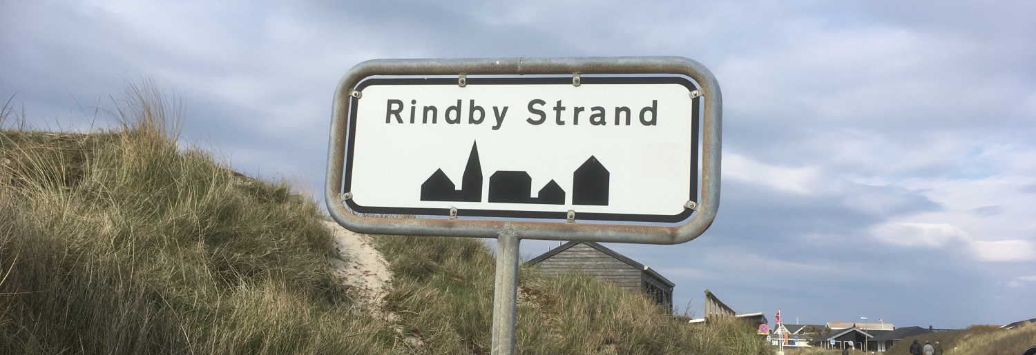 Rindby-skiltet med klitter og huse i baggrunden